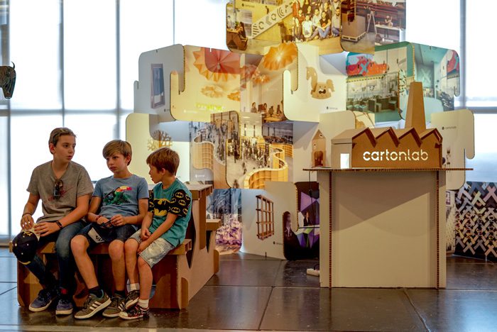Niños sentados en el stand de Cartonlab