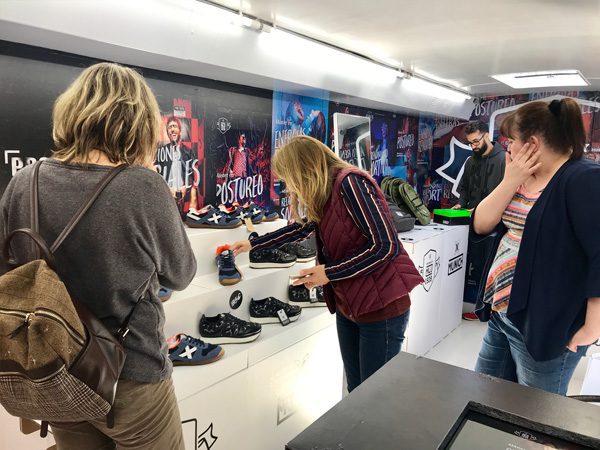 Jóvenes viendo las zapatillas Munich en expositor escalonado